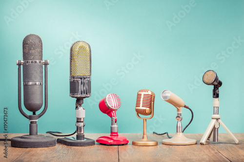 Retro old microphones for press conference or interview recording on table front gradient aquamarine background. Vintage old style filtered photo