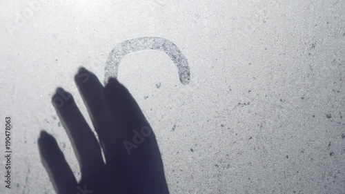 The glass of the window is swamped. Young girl with forefinger draws a symbol of love and heart. St. Valentine's Day