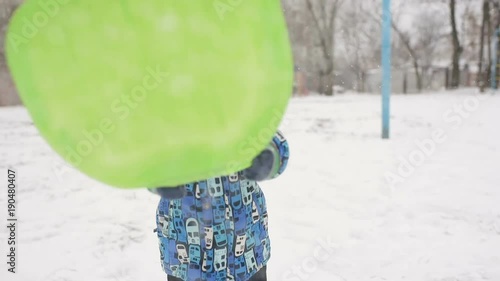 baby boy throws snow at the camera on winter background. photo