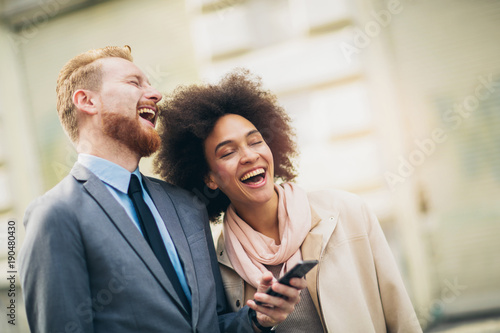 Happy business couple using smart phone outdoors