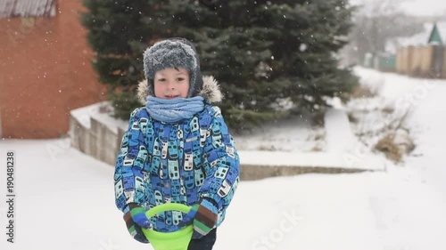 baby boy throws snow at the camera on winter background. photo