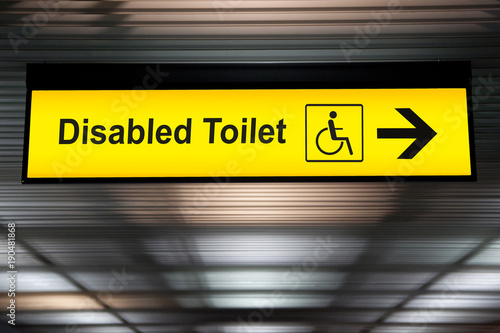sign with arrow point to disabled toilet at the airport for passenger with impaired body. universal design for elderly or the disabled in public place concept.