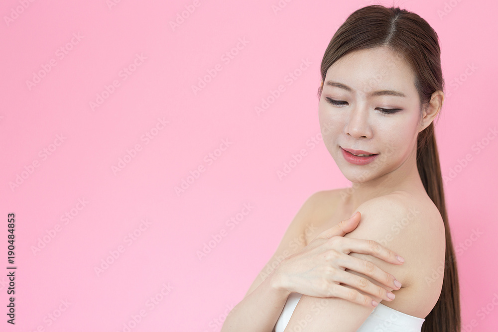 Beautiful Asian woman touching shoulder and smile with healthy skin,Isolated on pink background Beautiful Asian woman touching shoulder and smile with healthy skin,Isolated on pink background