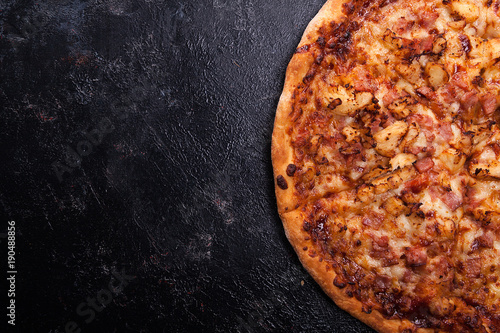 Top close up view of fresh baked pizza on dark wooden background with copy space available