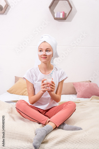 beautiful young woman with cosmetic facial patches with glass of milkshake at home
