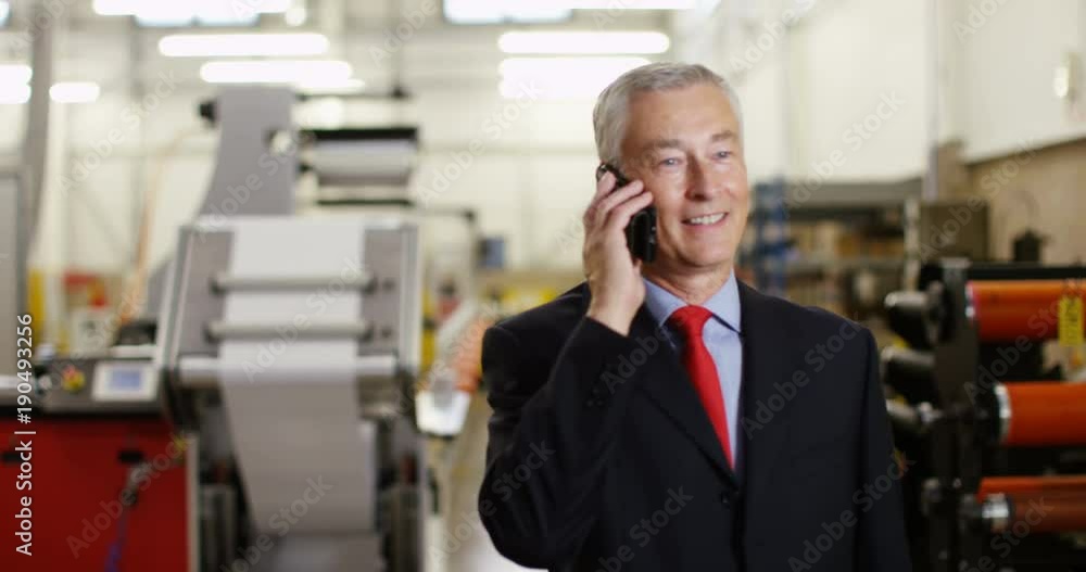 4K Happy mature businessman in factory talking on mobile phone. Crane shot panning downwards offering interesting change of background. Slow motion. 4K Happy mature businessman in factory talking on mobile phone. Crane shot panning downwards offering interesting change of background. Slow motion.