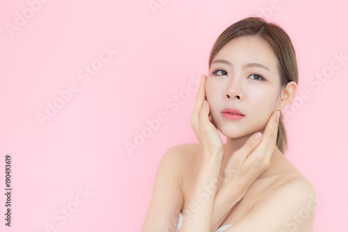 Asian beauty women stroking her face and perfect skin with copy space isolated on pink background