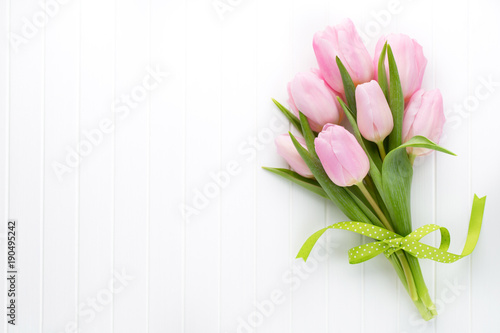 Fototapeta Naklejka Na Ścianę i Meble -  Fresh pink tulip flowers bouquet on shelf in front of wooden wall.