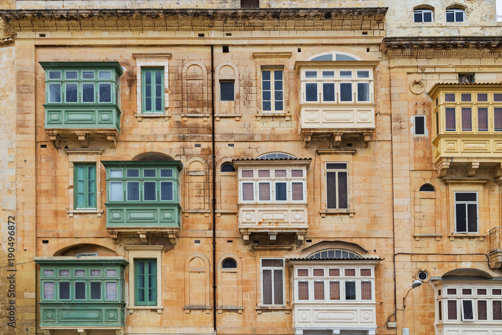 Traditional Maltese blue wooden balconies, typical yellow beige sandstone or limestone architecture in Valletta, capital city of Malta, known as Il-Belt.