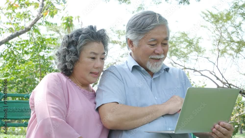 Asian couple elder people relax at park together. Elder people using laptop with happy emotion. People lifestyle concept 