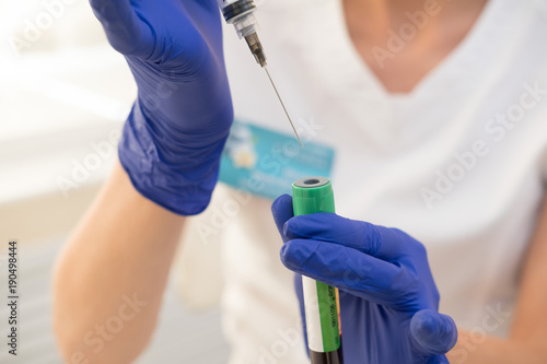 Syringe for medical injection in hands with blue gloves. Nurse or doctor. Liquid drug or narcotic. Health care in hospital. Needle mesotherapy.  Vaccination  medicine  research  cosmetology concept