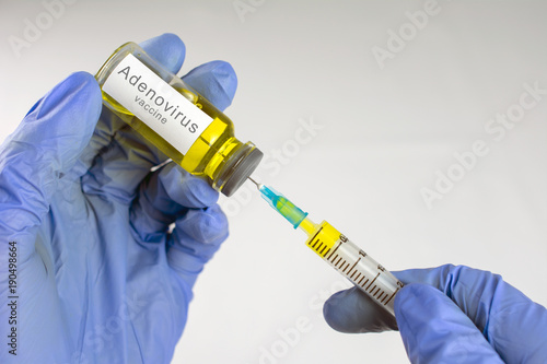 Hands in blue gloves are typing a yellow vaccine in a syringe. Adenovirus vaccination concept. close-up, selective focus