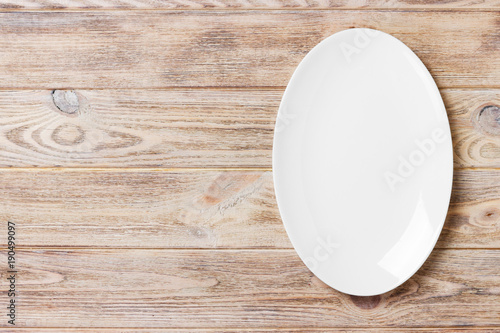 Top view of empty white food plate on a wood background