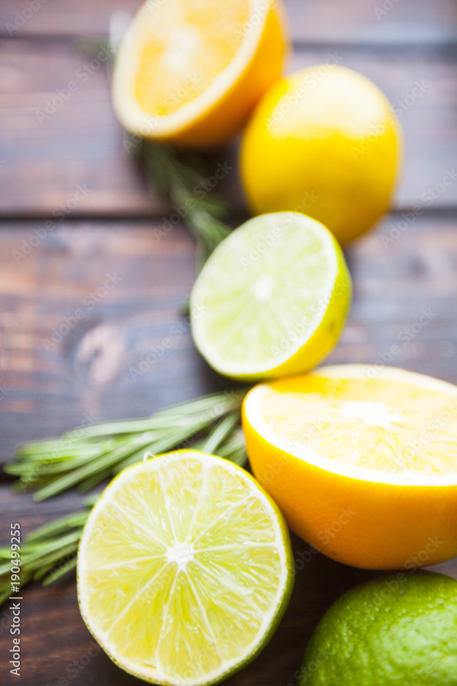 Fruit Tea, Cocktail, Dessert Concept. Cut and whole fresh oranges, lemons and limes with rosemary on a dark wooden table Fruit Tea, Cocktail, Dessert Concept. Cut and whole fresh oranges, lemons and limes with rosemary on a dark wooden table