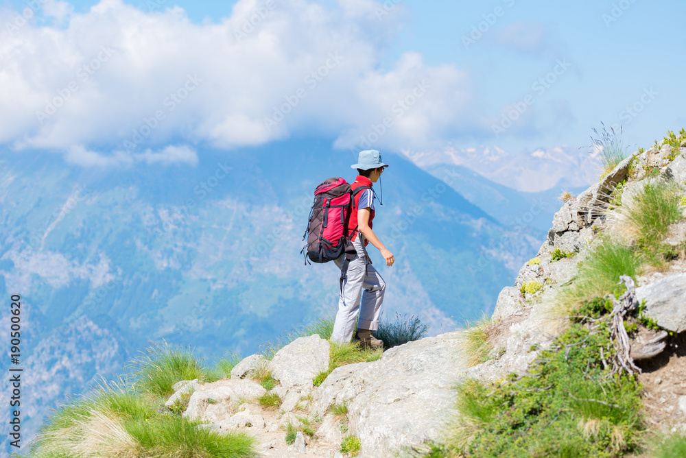 Backpacker walking on hiking trail in the mountain. Summer adventures summer vacation on the Alps. Wanderlust people traveling concept.