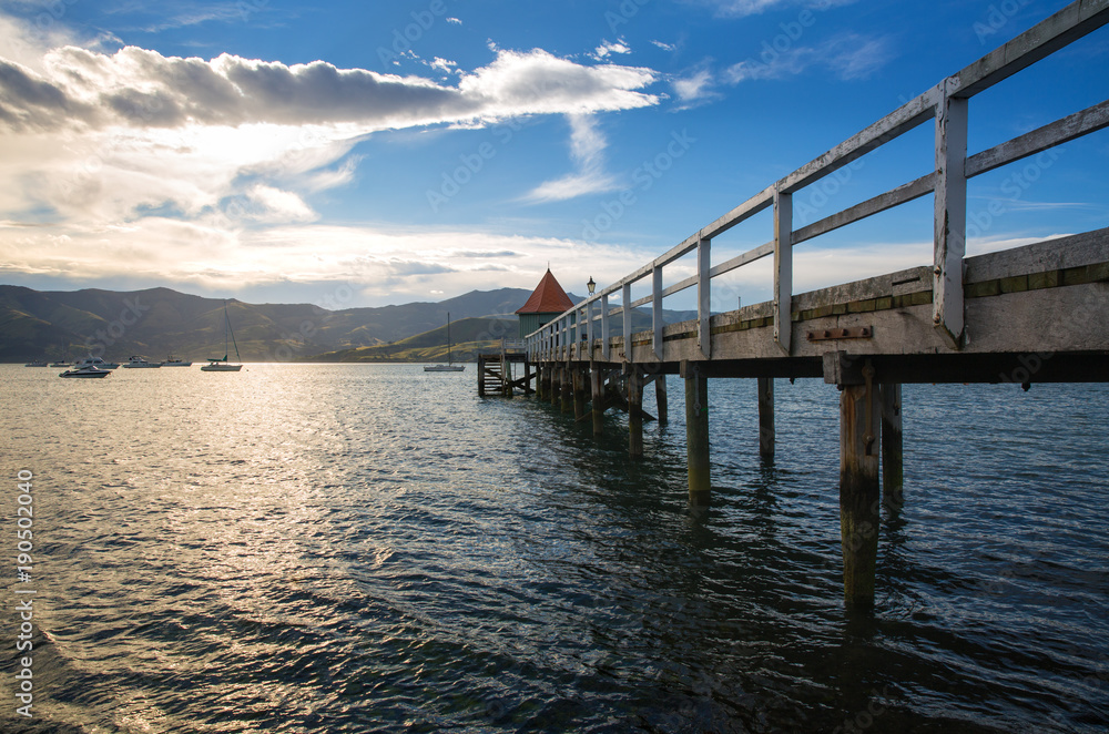 Sunset view of wooden pier in Akaroa bay, near Christchurch, New Zealand 