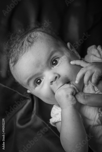 Portrait of a cute little mixed race baby sucking on her mom's index finger