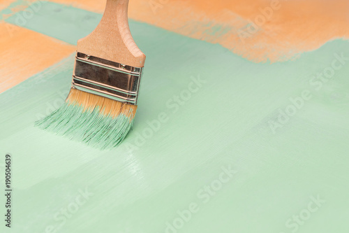 Staining wood surfaces with green paint using a paint brush