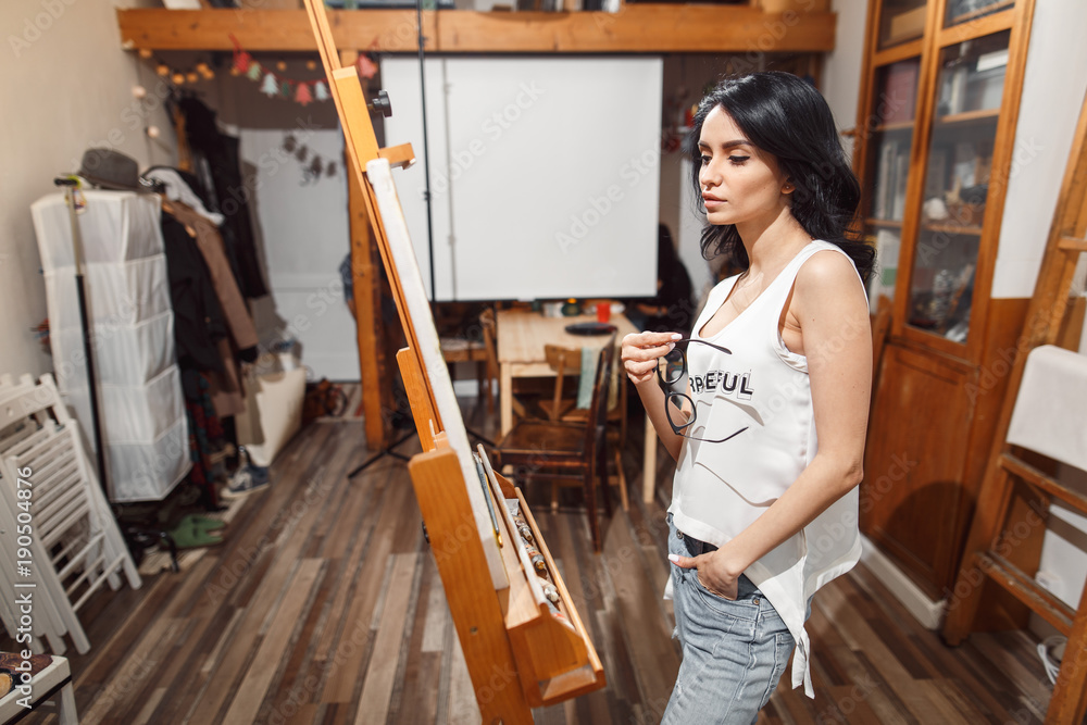 Smiling girl paints on canvas with oil colors in workshop Smiling girl paints on canvas with oil colors in workshop