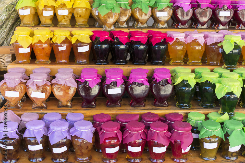 Traditional Greek sweet jam (jam) packed in jars with colorful lids on the shelf of the shop