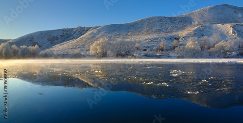 Freezing river from the hilly banks and large ice floes. A sunny day with a cloudless sky.