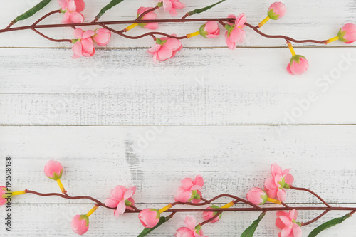 Fake pink flower branches on white wood background with copy space