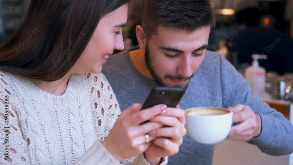 Couple using mobile phone while dating at cafe Couple using mobile phone while dating at cafe