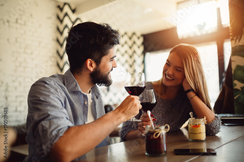 Portrait of a beautiful romantic couple drinking red wine while celebrating Valentine's Day in cafe.