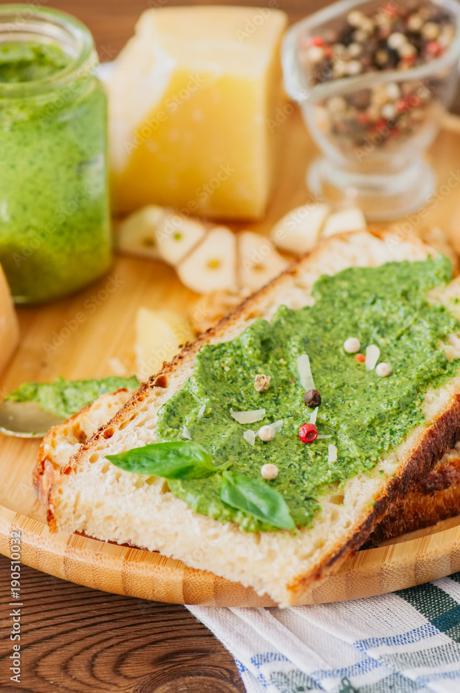 Bruschetta with basil walnut pesto sauce on a wooden plate. Wooden backdrop. Bruschetta with basil walnut pesto sauce on a wooden plate. Wooden backdrop.