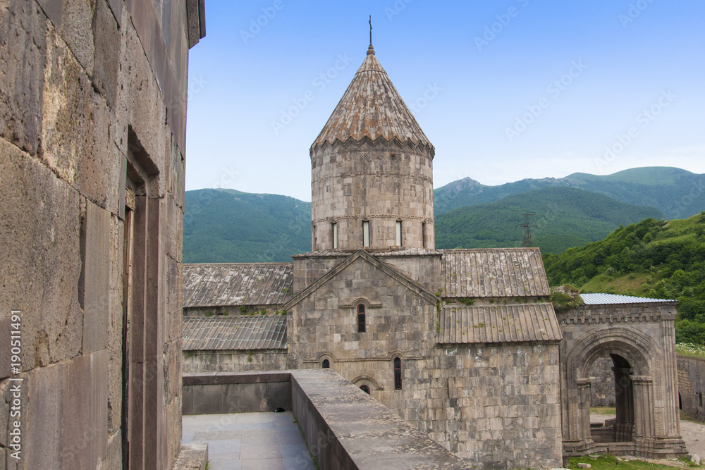 Surb Pogos-Petros Cathedral, Tatev Monastery - Armenian Apostolic Monastery of IX century. Mountains, green hills and clear blue sky. Armenia.
