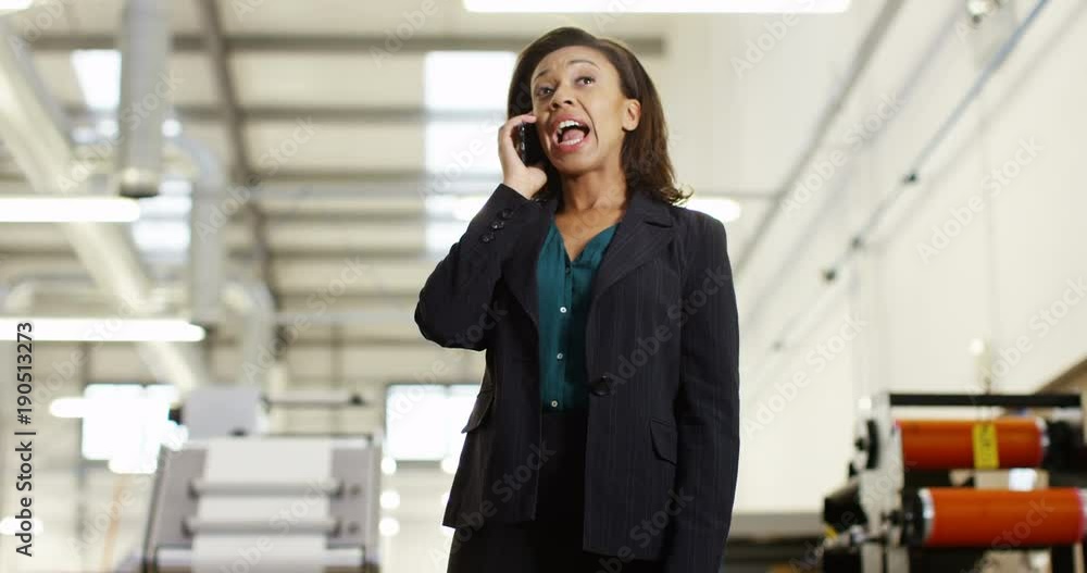 4K Frustrated & annoyed businesswoman in factory dealing with business problems over the phone. Slow motion.