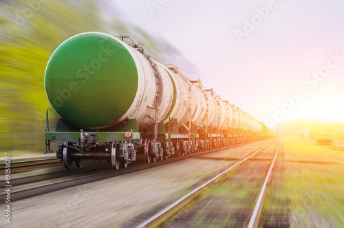 Freight train passing oil-loading, fuel oil, fuel tanks in motion.