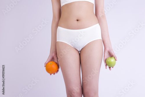 Healthy beautiful woman holding fruits. Healthy fitness and eating lifestyle concept. Apple and orange.