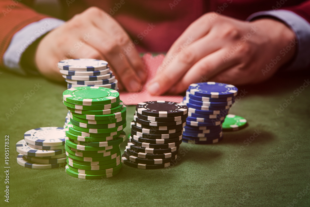 chips in the foreground, in the blurring of the hands of a man holding two cards, playing poker. without face chips in the foreground, in the blurring of the hands of a man holding two cards, playing poker. without face