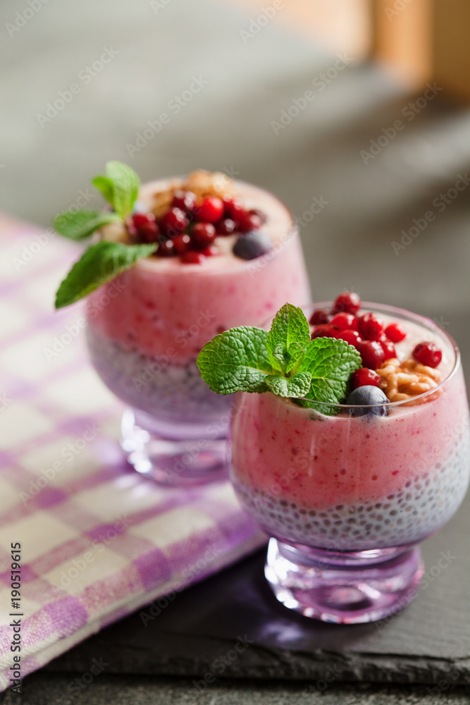Layered chia, banana and berry smoothie garnished with fresh mint, healthy food style on black slate background Layered chia, banana and berry smoothie garnished with fresh mint, healthy food style on black slate background