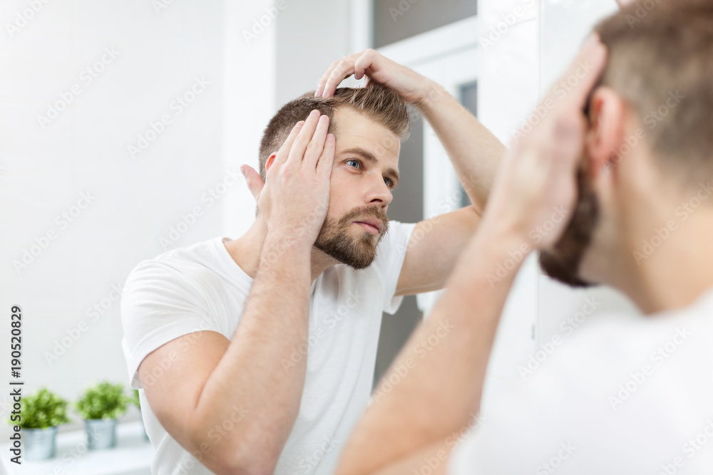 Handsome young man worried about hairloss Handsome young man worried about hairloss