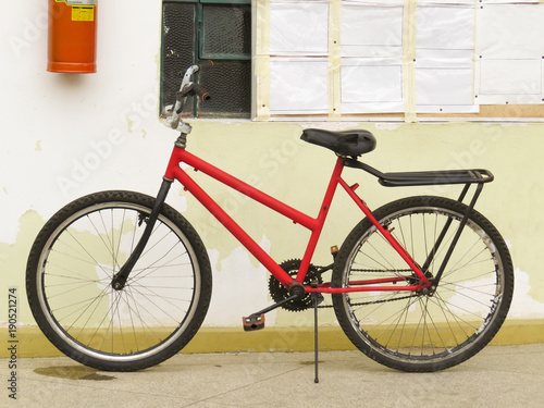 Old and worn red bike, abandoned leaning against the wall too worn