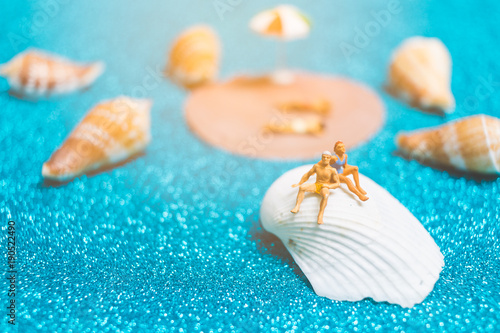 Miniature people wearing swimsuit relaxing on a seashell