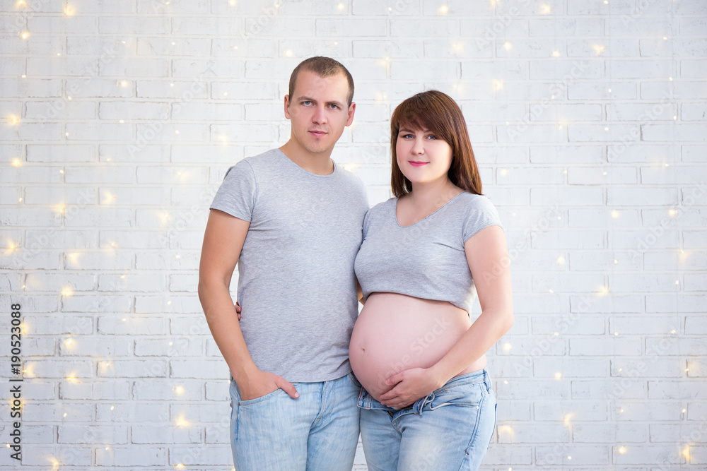portrait of happy pregnant couple over white brick wall portrait of happy pregnant couple over white brick wall