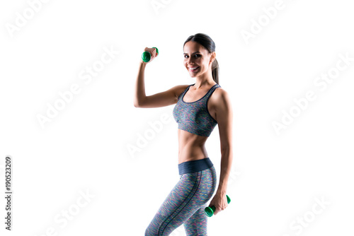 Attractive beautiful sporty healthy woman wearing tight clothes is doing exercises using dumbbells, isolated on white background