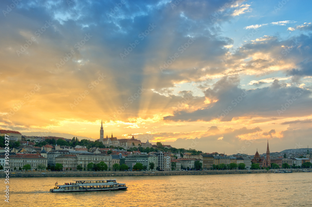 Scenic sunset, sun rays through clouds. Danube river and Budapest city