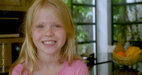 Blond haired little girl with freckles smiling and looking at camera