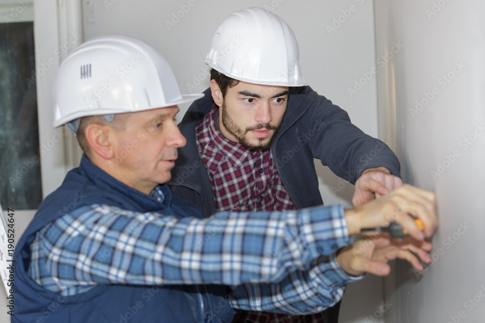 two workmen measureing wall two workmen measureing wall