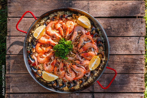 Traditional seafood paella in the fry pan on a wooden old table, top view