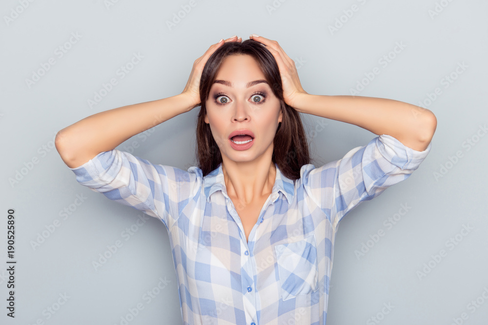No way! Portrait of pretty, surprised, shocked woman with wide opened mouth and eyes in checkered shirt touching head with two hands isolated on grey background No way! Portrait of pretty, surprised, shocked woman with wide opened mouth and eyes in checkered shirt touching head with two hands isolated on grey background