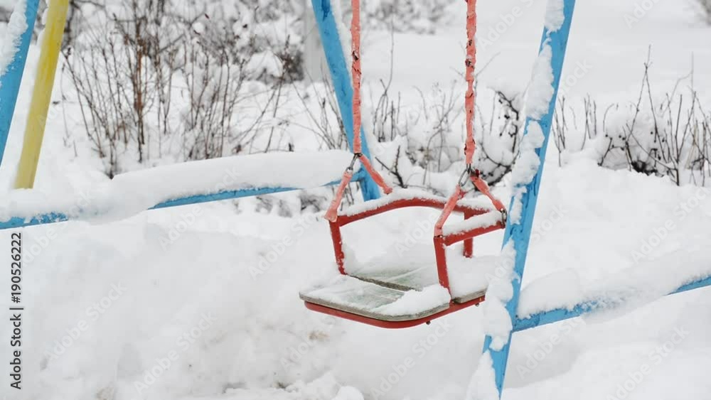 snow covered swing at a playground in winter