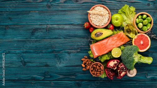 Healthy food. Fish salmon, avocado, broccoli, fresh vegetables, nuts and fruits. On a wooden background. Top view. Copy space.