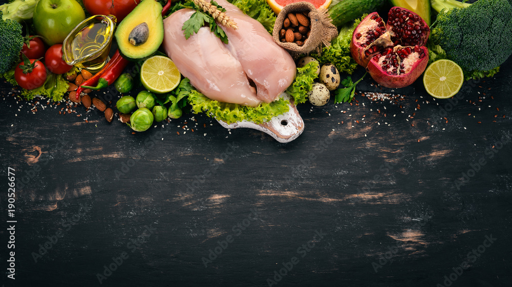 Healthy food. Chicken fillet, avocado, broccoli, fresh vegetables, nuts and fruits. On a wooden background. Top view. Copy space.