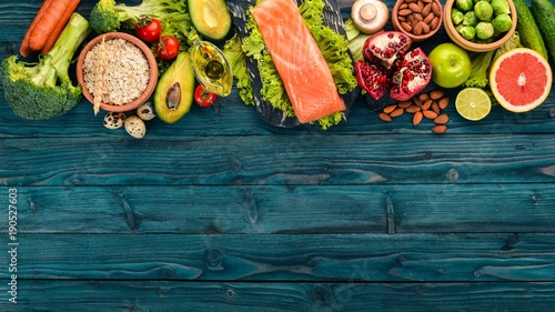 Plakat Zdrowe jedzenie. Ryby z łososia, awokado, brokuły, świeże warzywa, orzechy i owoce. Na drewnianym tle. Widok z góry. Skopiuj miejsce.