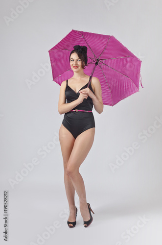 Woman in black bikini with umbrella .